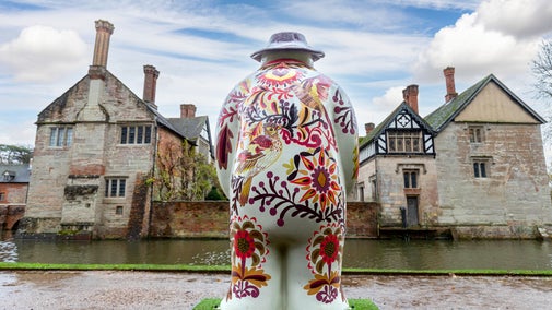 A back view of a colourful Snowman™ looking out over the moat at Baddesley Clinton, Warwickshire